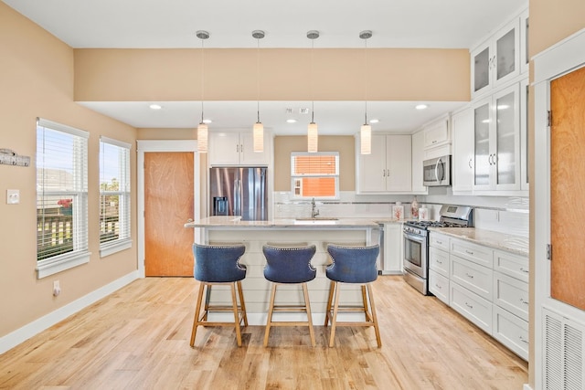 kitchen featuring a kitchen island, pendant lighting, appliances with stainless steel finishes, and white cabinets