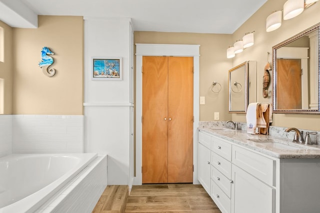 bathroom with vanity, hardwood / wood-style floors, and a relaxing tiled tub