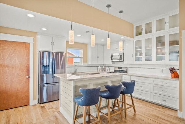 kitchen with white cabinetry, stainless steel appliances, a center island, and light hardwood / wood-style flooring