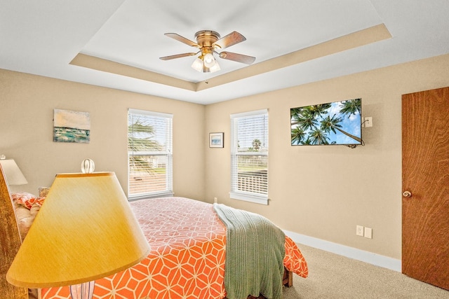 carpeted bedroom featuring ceiling fan and a tray ceiling