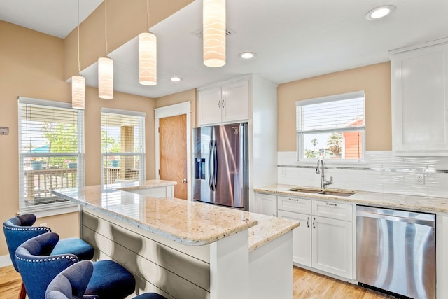 kitchen featuring white cabinetry, appliances with stainless steel finishes, hanging light fixtures, sink, and a kitchen breakfast bar