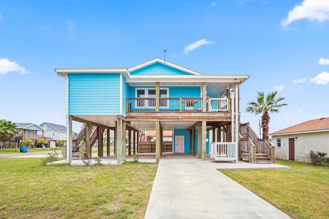 raised beach house with a front lawn, covered porch, and a carport