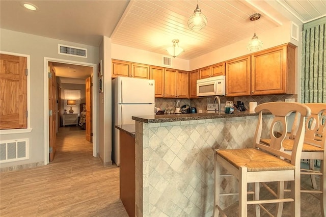 7477 State Highway 361 Unit 107, Port Aransas, TX 78373 - kitchen featuring white appliances, a peninsula, light wood-style floors, decorative backsplash, and brown cabinets