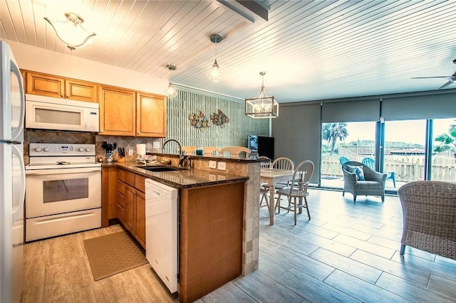 7477 State Highway 361 Unit 107, Port Aransas, TX 78373 - kitchen with white appliances, a peninsula, light wood-style floors, decorative backsplash, and dark stone countertops