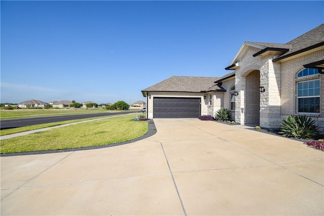 3002 N Oso Pkwy, Corpus Christi, TX 78414 - view of home's exterior with an attached garage, driveway, a yard, brick siding, and a shingled roof