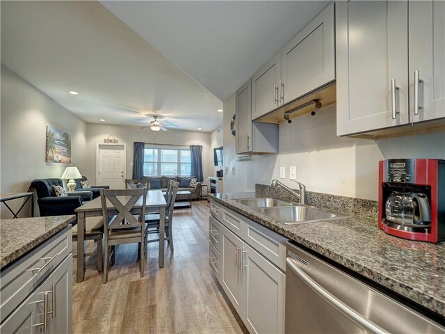 kitchen with light stone countertops, stainless steel dishwasher, ceiling fan, sink, and light hardwood / wood-style floors