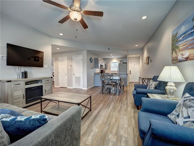 living room with light wood-type flooring and ceiling fan