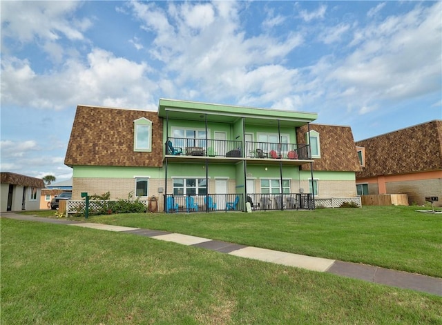 back of property with a yard and a balcony