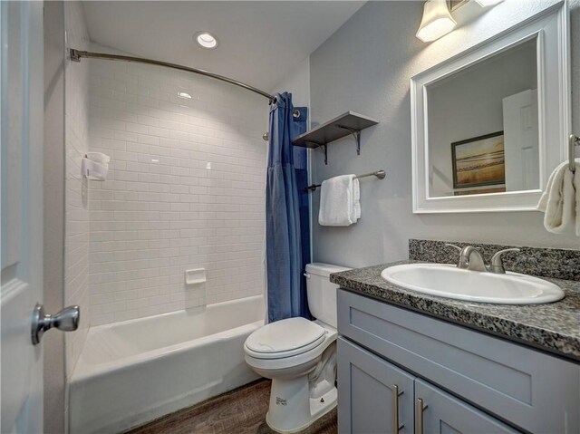 full bathroom with shower / tub combo with curtain, vanity, wood-type flooring, and toilet