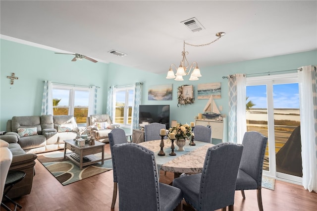 dining space with ceiling fan with notable chandelier and wood-type flooring