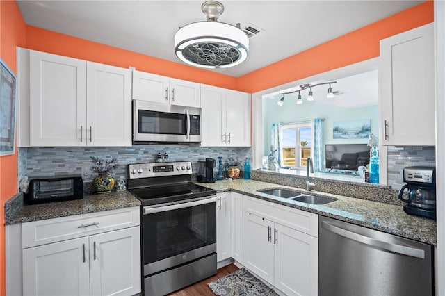 kitchen featuring tasteful backsplash, sink, stainless steel appliances, white cabinets, and stone countertops