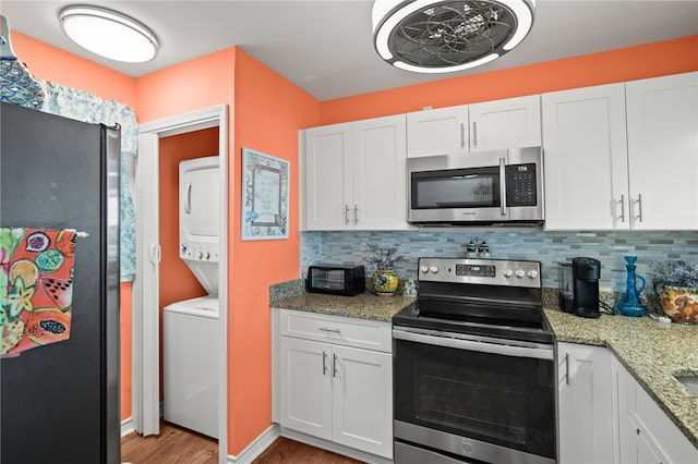 kitchen featuring white cabinets, appliances with stainless steel finishes, stacked washing maching and dryer, and light wood-type flooring