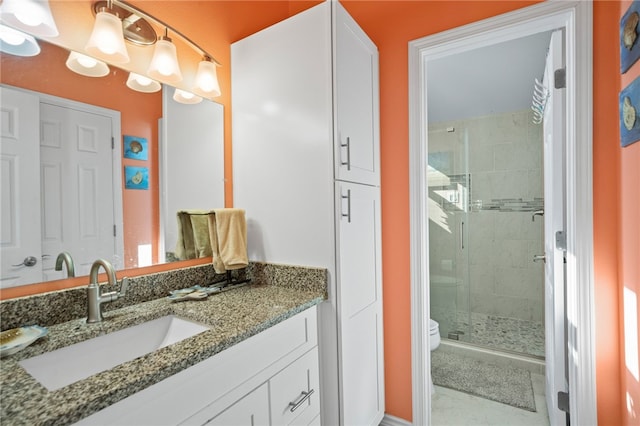 bathroom featuring toilet, tile patterned flooring, a shower with shower door, and vanity