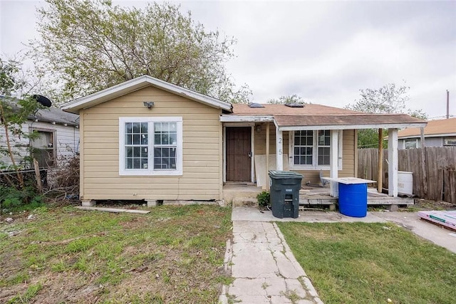 bungalow-style house with a front lawn, roof with shingles, and fence