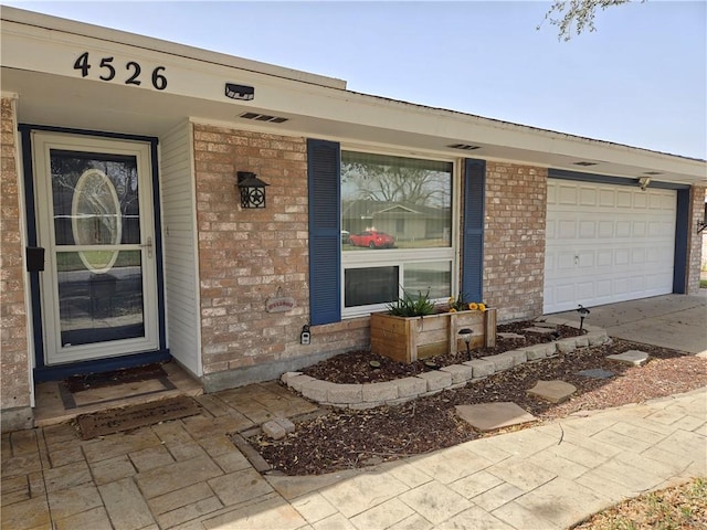 property entrance featuring a garage, driveway, and brick siding