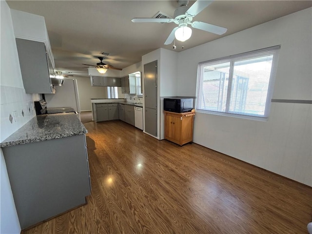 kitchen featuring dark wood-style floors, white dishwasher, gray cabinets, black microwave, and a sink