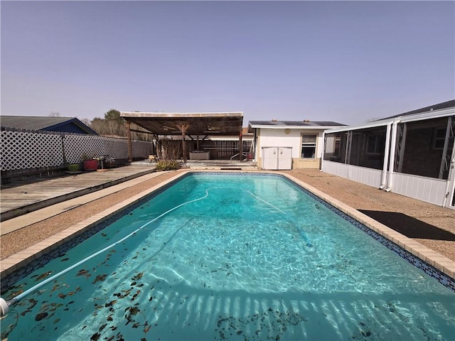 view of pool with a fenced in pool, a sunroom, a fenced backyard, and a deck