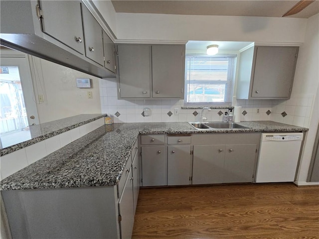 kitchen with dark wood-style flooring, a sink, gray cabinets, dishwasher, and tasteful backsplash