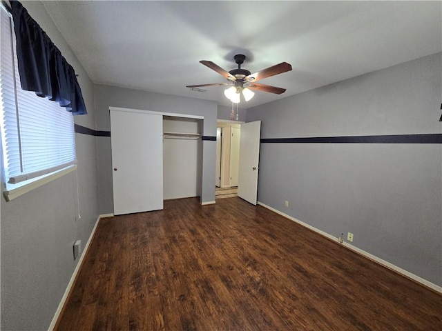 unfurnished bedroom featuring ceiling fan, a closet, baseboards, and dark wood-type flooring