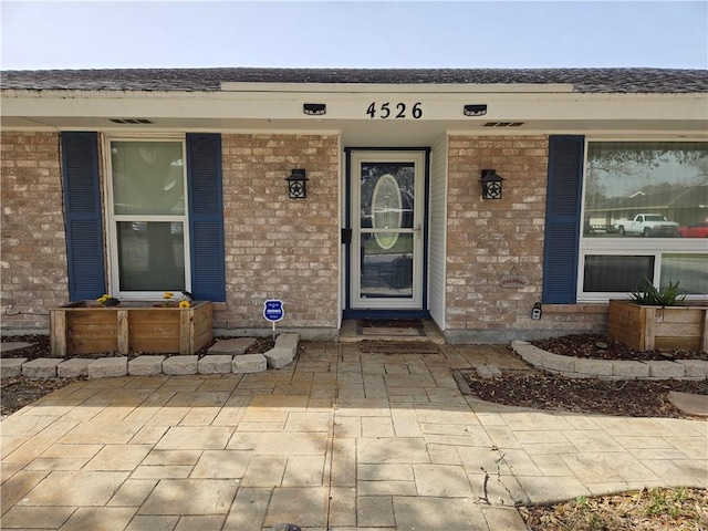 doorway to property featuring covered porch and brick siding