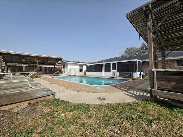 view of pool with a fenced in pool, an outbuilding, a sunroom, and a wooden deck