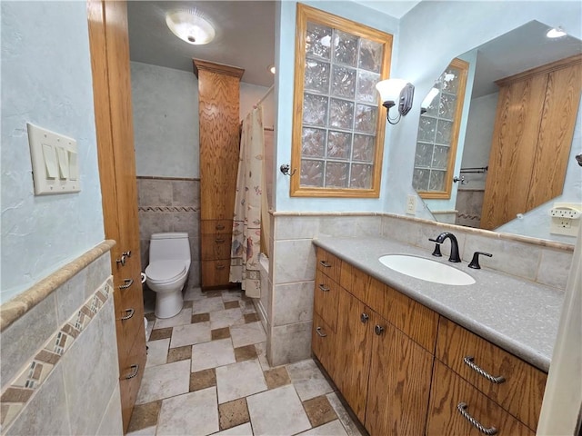 bathroom with toilet, tile walls, and vanity