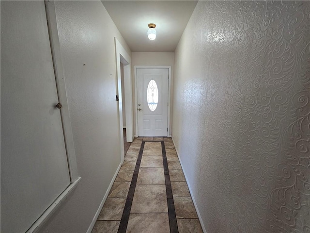 entryway with a textured wall, tile patterned floors, and baseboards