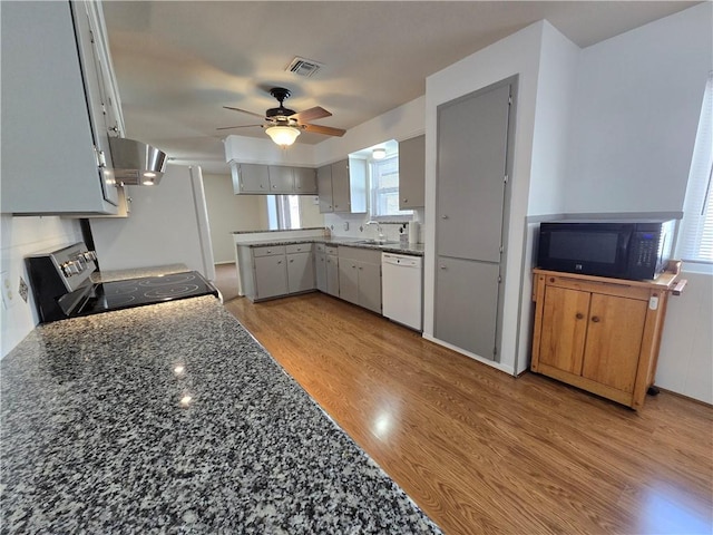 kitchen with black microwave, visible vents, dishwasher, wall chimney exhaust hood, and stainless steel electric range oven