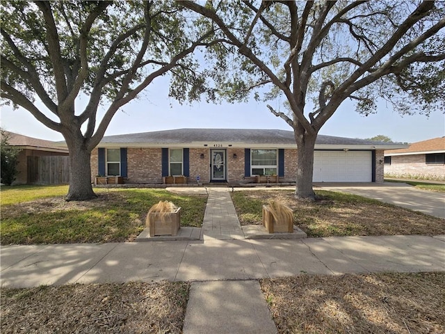 ranch-style house with driveway, brick siding, and an attached garage