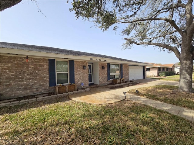 ranch-style home with a garage, a front yard, concrete driveway, and brick siding