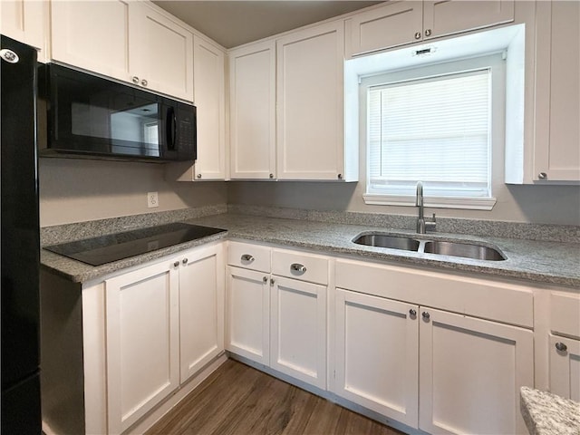 1021 Dona Dr, Corpus Christi, TX 78407 - kitchen with black appliances, a sink, white cabinets, dark wood-style flooring, and light countertops
