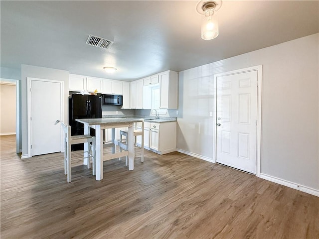 1021 Dona Dr, Corpus Christi, TX 78407 - kitchen with black appliances, baseboards, white cabinetry, and wood finished floors