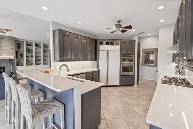 kitchen featuring backsplash, a ceiling fan, appliances with stainless steel finishes, and a peninsula