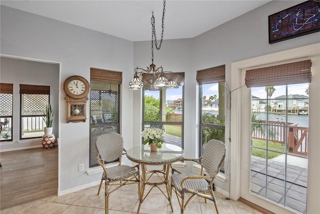 dining space with baseboards, a water view, and a notable chandelier