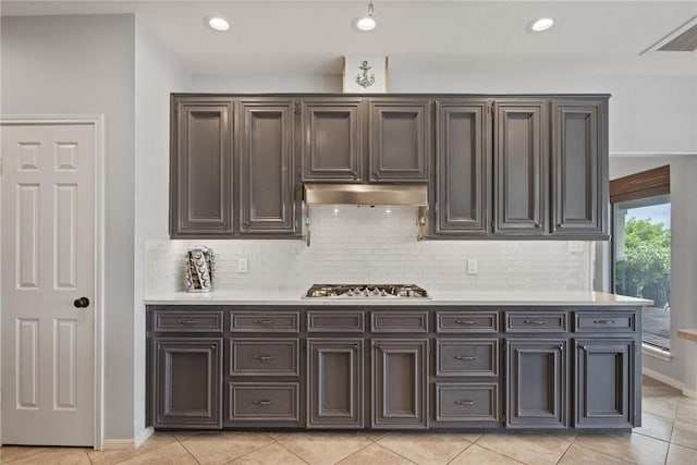 kitchen featuring light countertops, baseboards, decorative backsplash, and light tile patterned floors