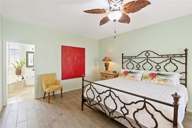 bedroom with baseboards, a ceiling fan, ensuite bath, and wood finished floors