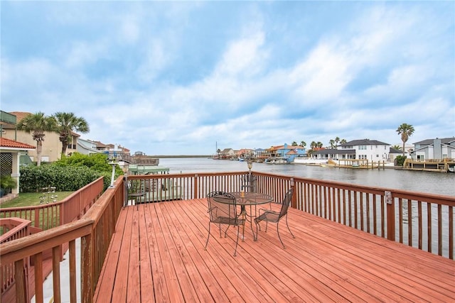wooden deck featuring a water view, a residential view, and outdoor dining space