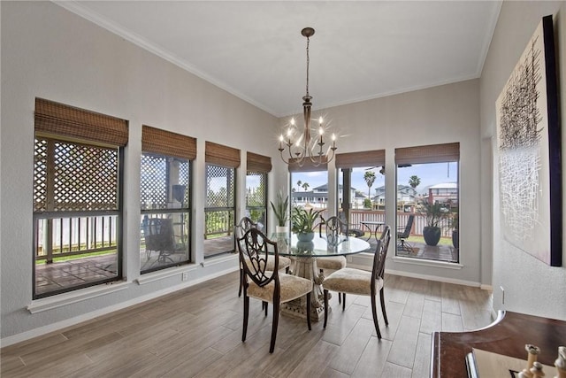 dining space with baseboards, ornamental molding, wood finished floors, and a chandelier