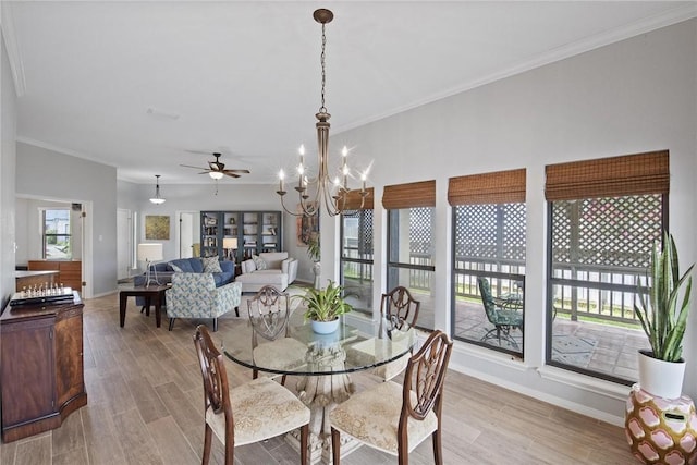 dining room featuring light wood-type flooring, ornamental molding, baseboards, and ceiling fan with notable chandelier