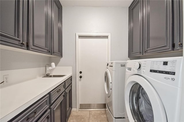 clothes washing area with a sink, light tile patterned floors, cabinet space, and washer and dryer