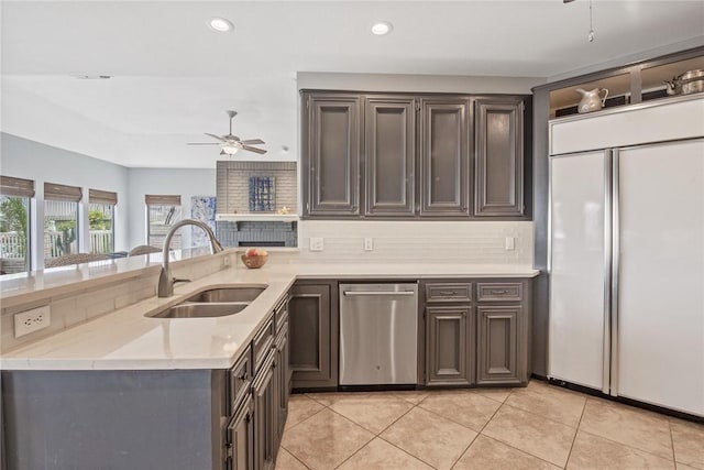 kitchen featuring a sink, dishwasher, a ceiling fan, backsplash, and paneled fridge