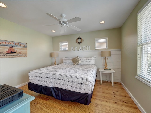 bedroom with ceiling fan, multiple windows, and light hardwood / wood-style flooring