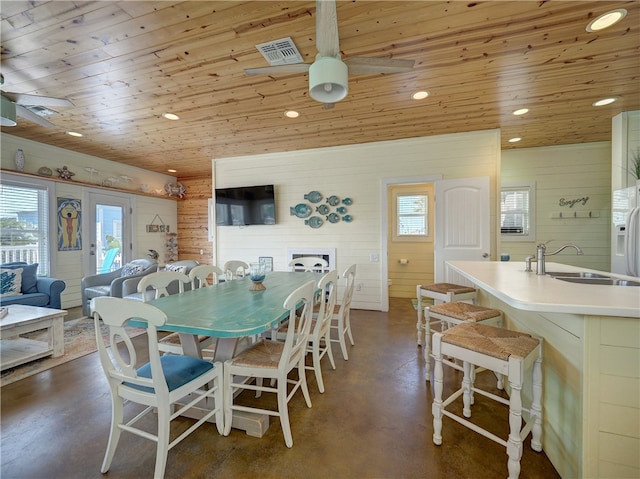 dining area featuring wood walls, sink, ceiling fan, and wood ceiling