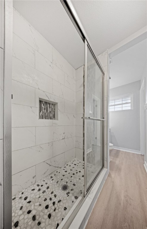 1333 Prince Dr, Corpus Christi, TX 78412 - full bathroom featuring a shower stall, wood finished floors, toilet, and baseboards