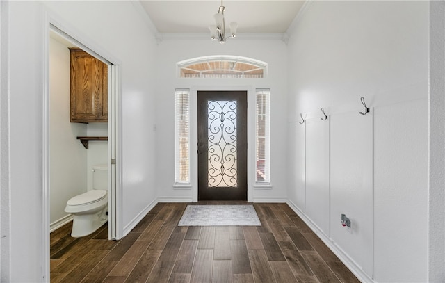 foyer entrance featuring dark wood-style floors, a notable chandelier, baseboards, and ornamental molding