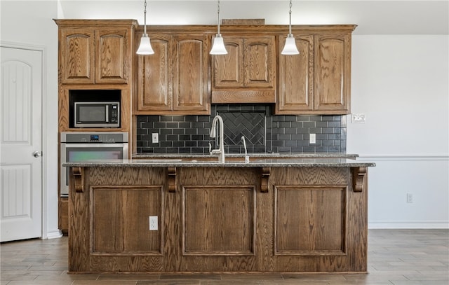 kitchen featuring wood finished floors, backsplash, stainless steel appliances, and a sink