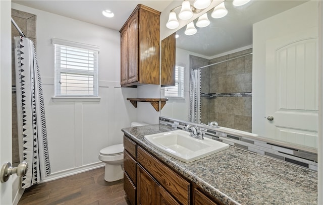 full bathroom featuring vanity, toilet, wood finished floors, and a tile shower