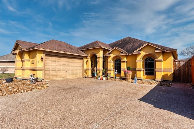 view of front of home featuring stucco siding, a garage, driveway, and fence