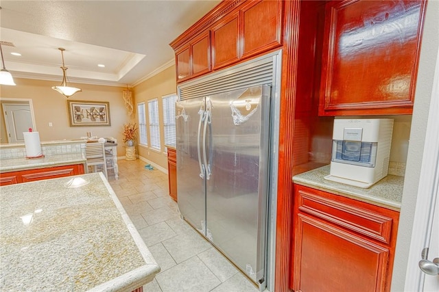 kitchen with baseboards, pendant lighting, built in refrigerator, a tray ceiling, and ornamental molding