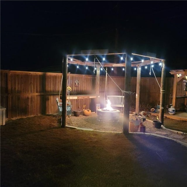 patio at twilight with a fire pit and a fenced backyard